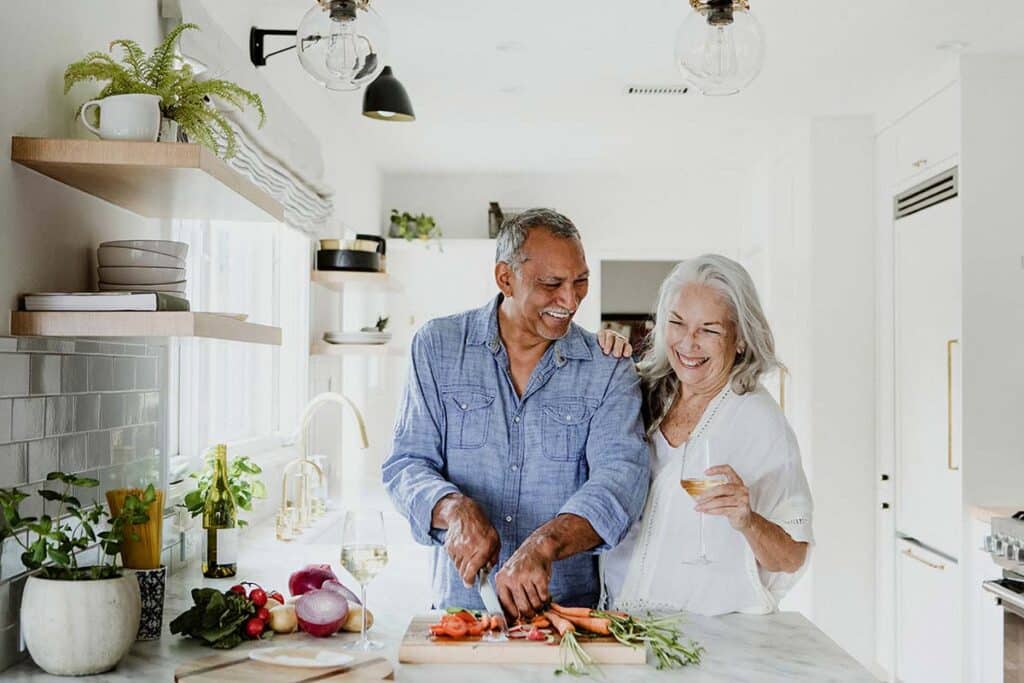 Older couple enjoying a healthy meal together in the kitchen, highlighting the benefits of Osteo Naturals products for bone health and overall wellness.