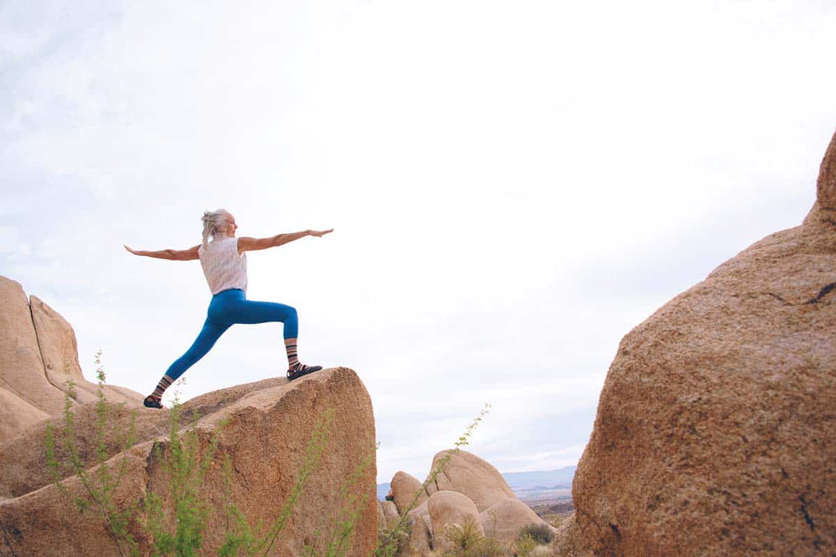 Senior woman practicing yoga on rocks, emphasizing the importance of exercise for bone health and understanding bone density tests